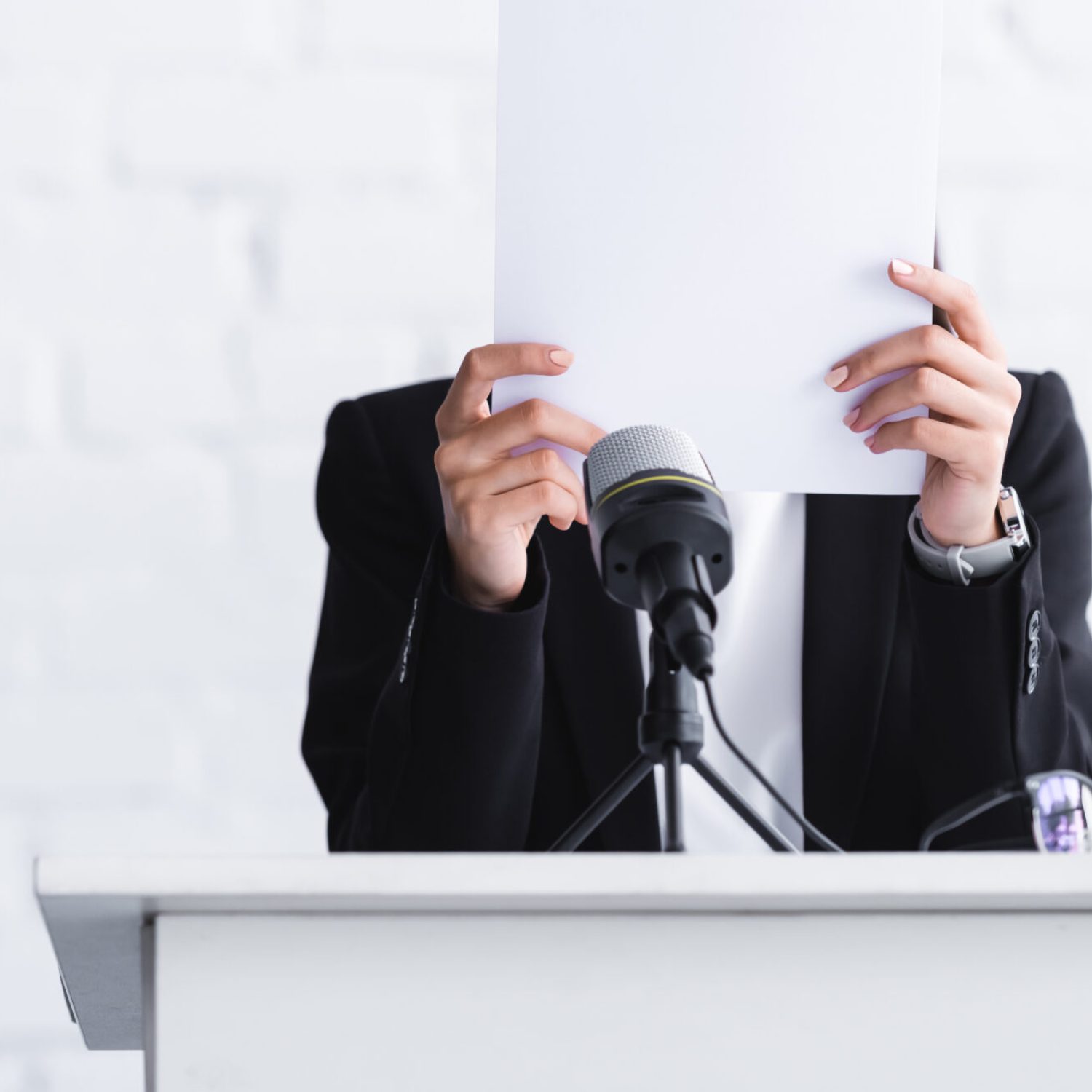 young lecturer, suffering from fear of public speaking, standing on podium tribune and hiding face